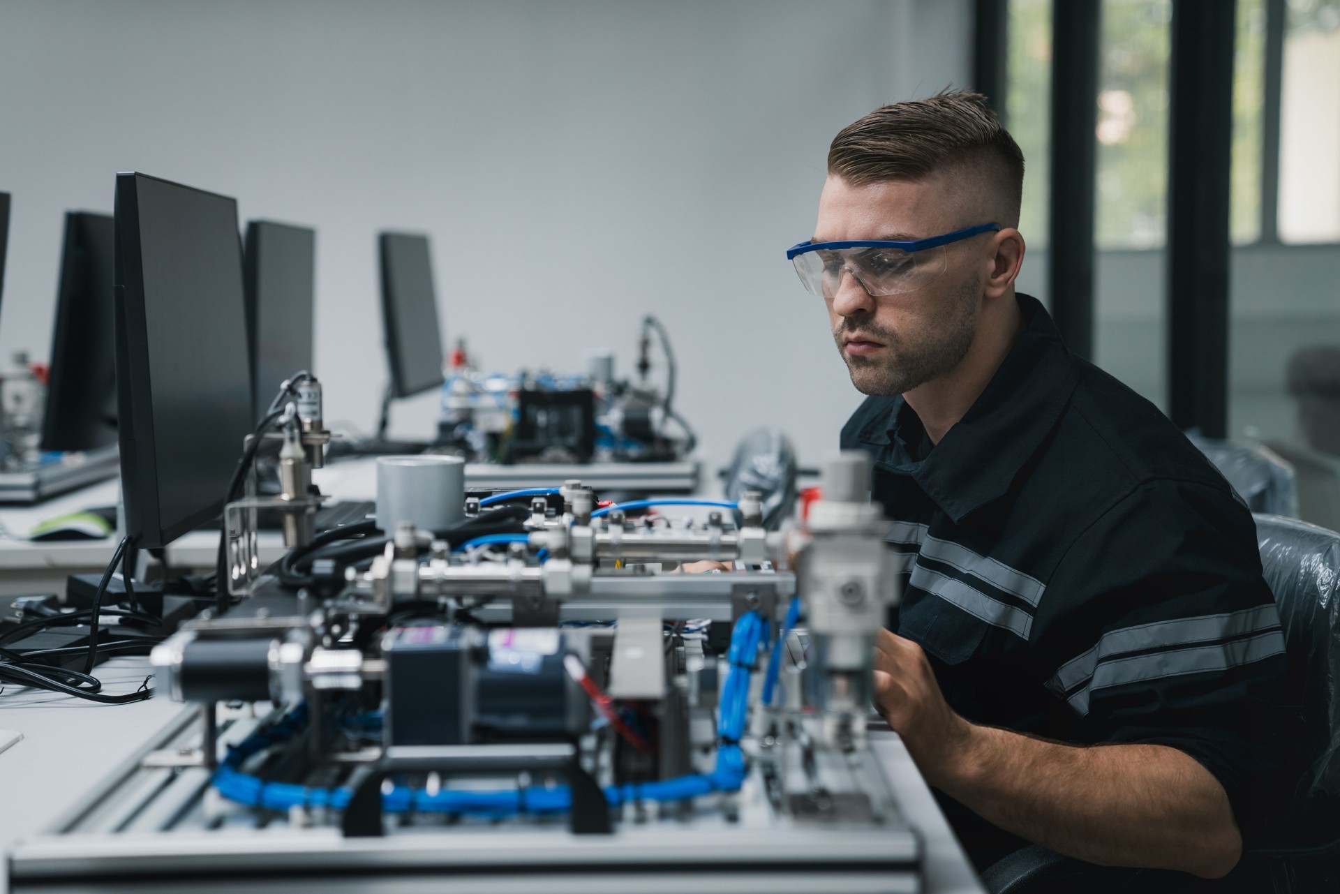 Student engineer Assembling Robotic Arm with computer in Technology Workshop. Service Engineer Holding Robot Controller and Checking Robotic Arm Welding Hardware.