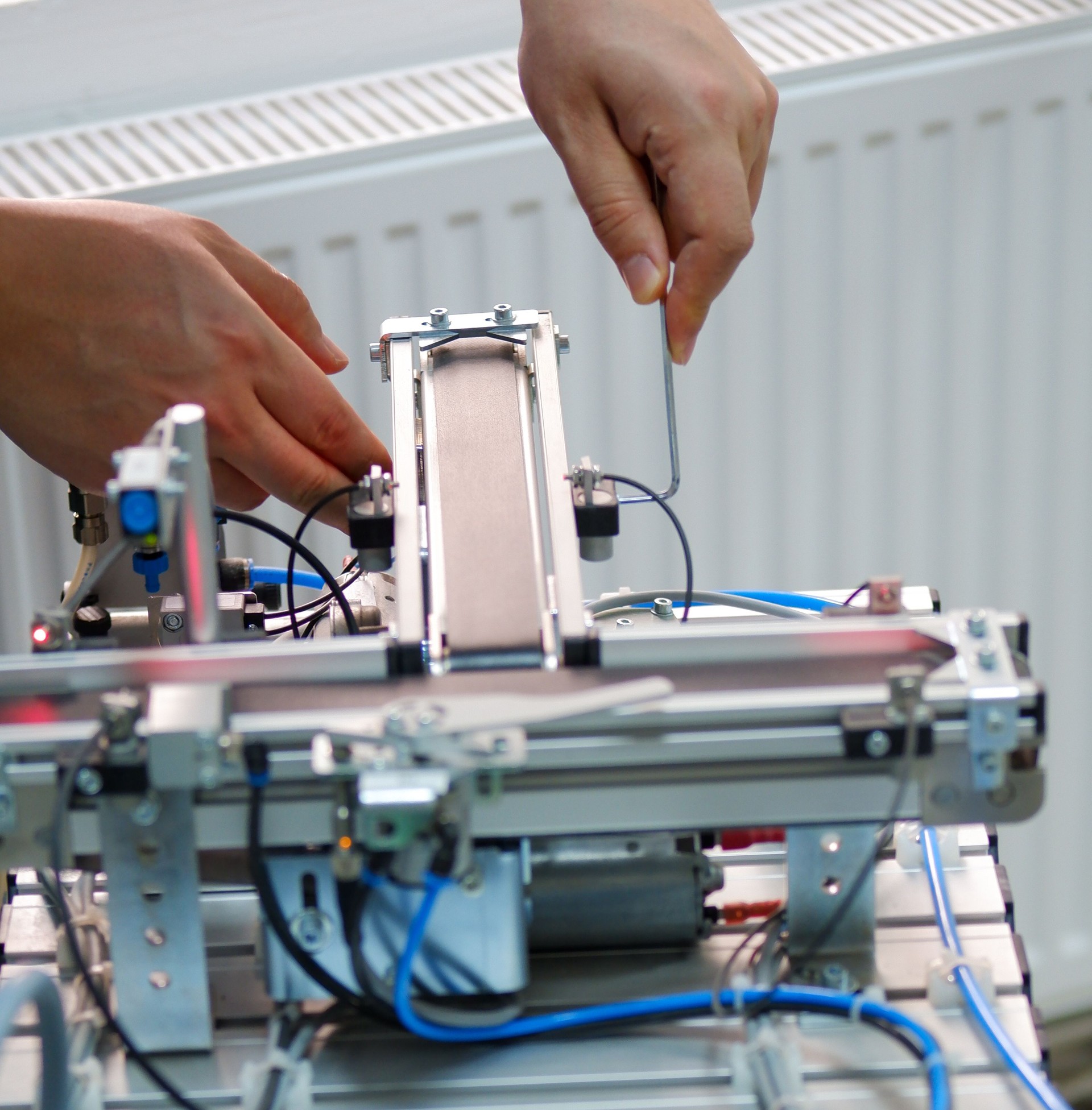 Closeup of male technician repairing automation system's electronic card by allen key.